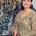 a women in golden lehenga wearing jewellery and makeup on face smiling