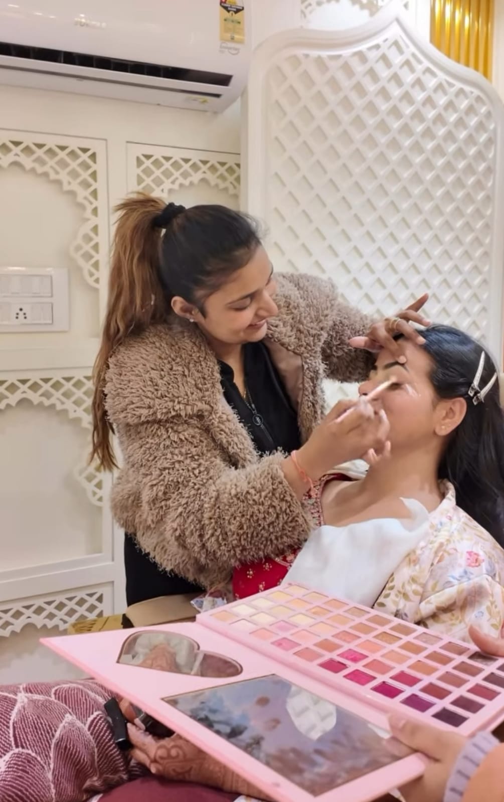 smiling makeup artist doing makeup on client