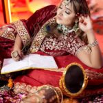 a women in maroon lehenga with makeup and jewellery posing