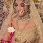 a women wearing golden bridal wear with wearing jewellery and makeup on face posing