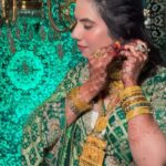 a women in bottle green lehenga and wearing heavy jewelery and makeup on face posing