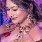 a women with makeup on face smiling and showcasing her jewellery
