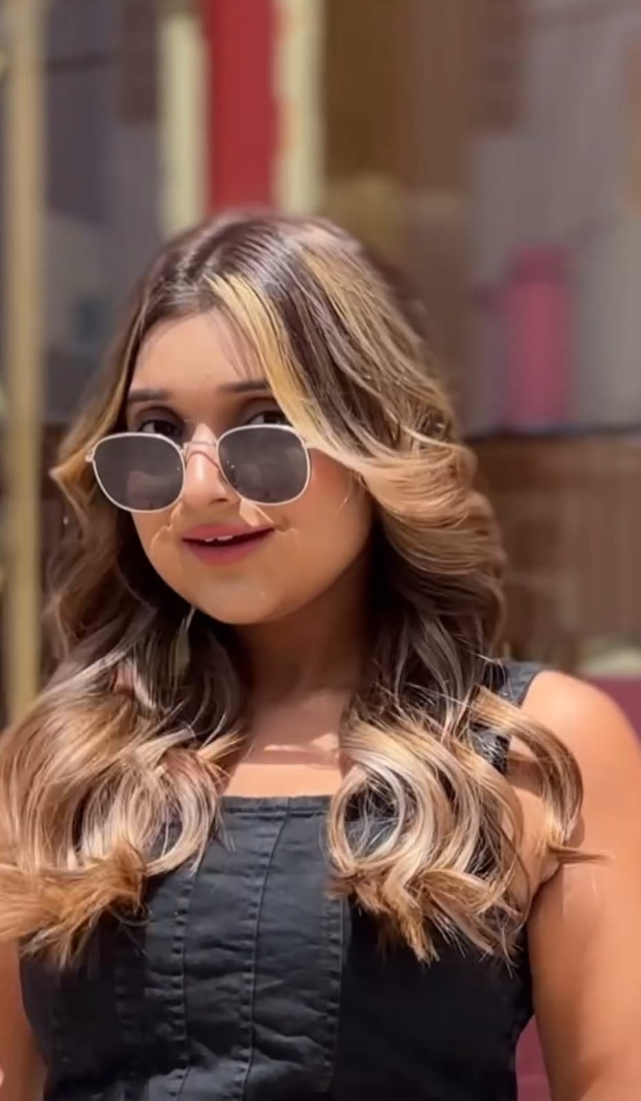 a women with brown highlighted hair and shades on face posing