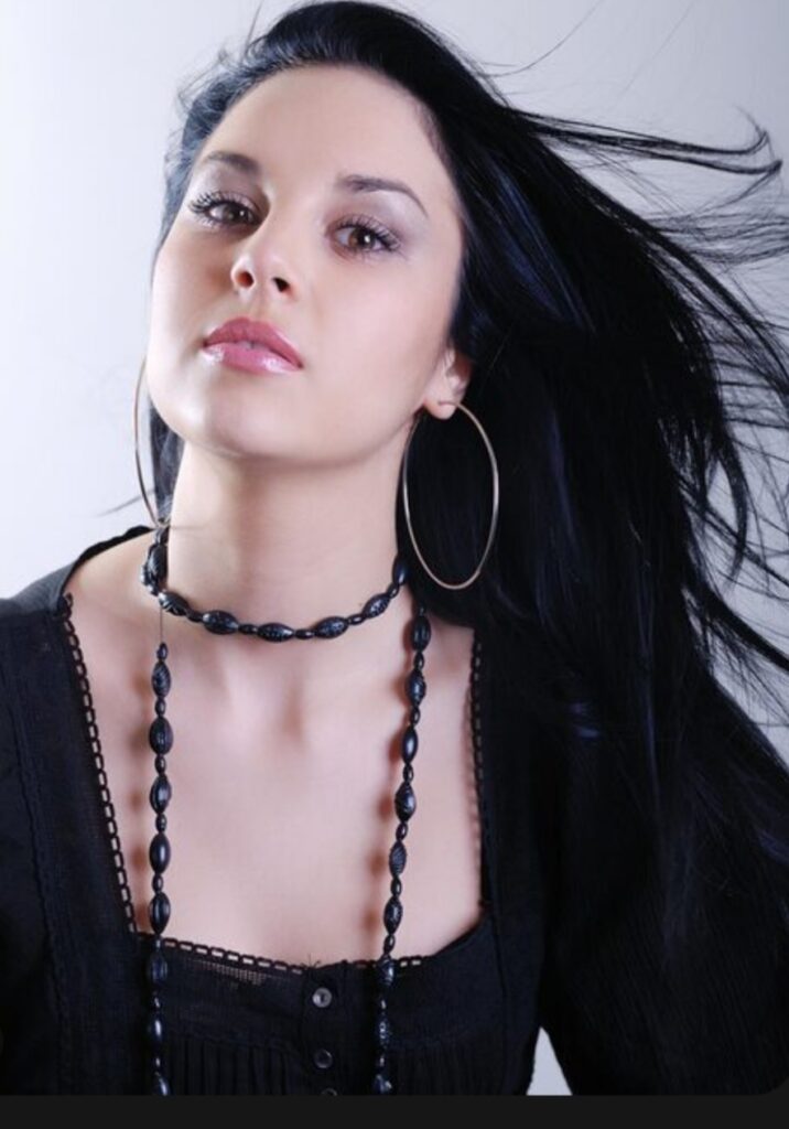 a girl in black top wearing funky earrings and hair is straight long