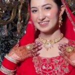 a punjabi women in red bridal dress had worn jewellery and makeup ,smiling and looking at the camera beautifully